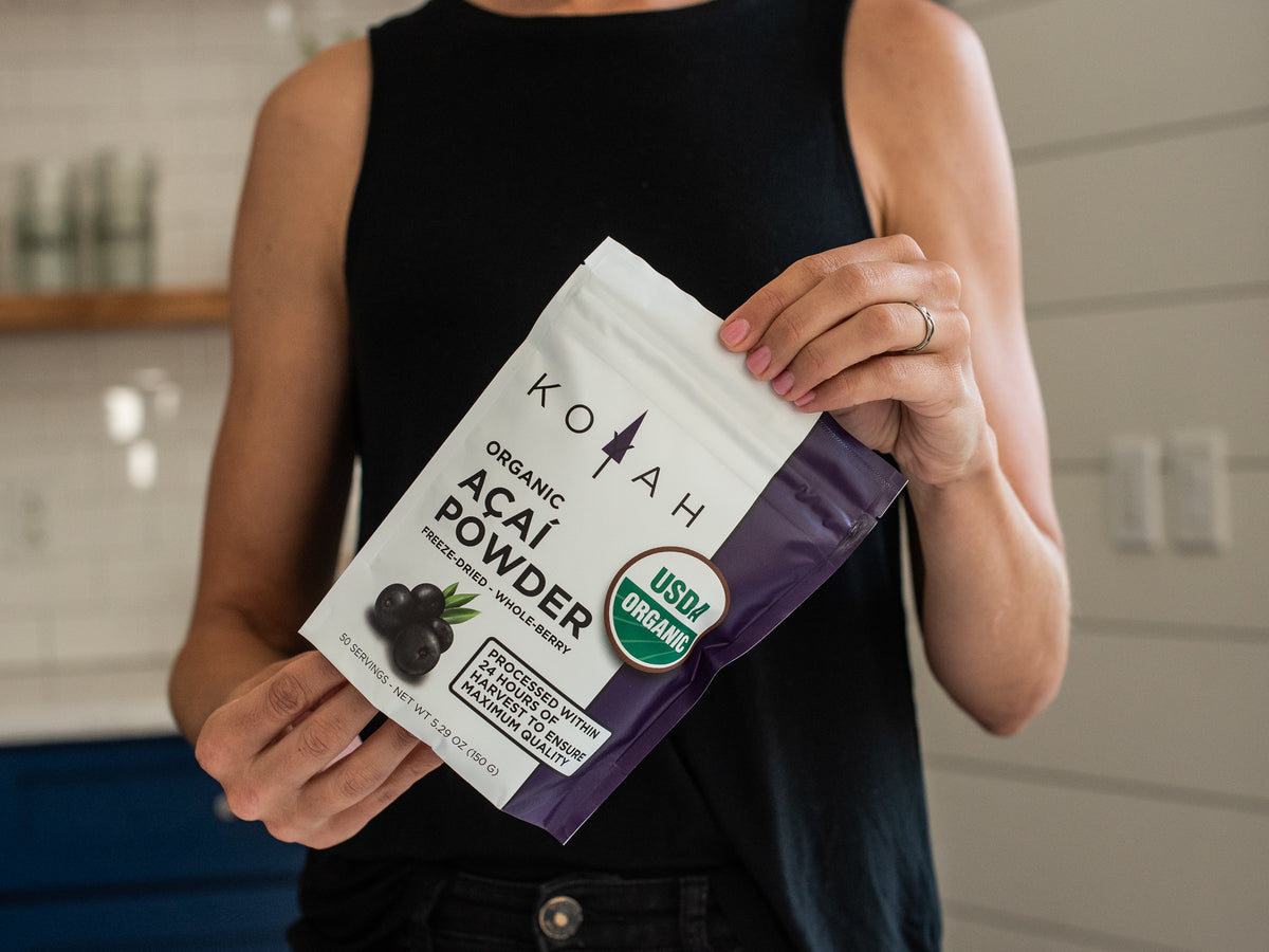 Person holding KOYAH Organic Acai Powder pouch — freeze-dried whole-berry acai, USDA organic certified